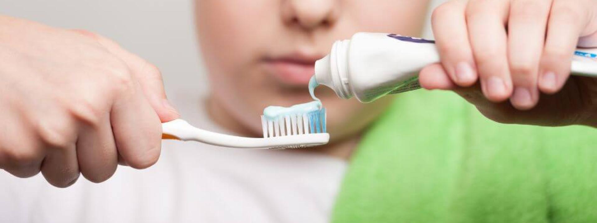 Boy putting toothpaste on his toothbrush.