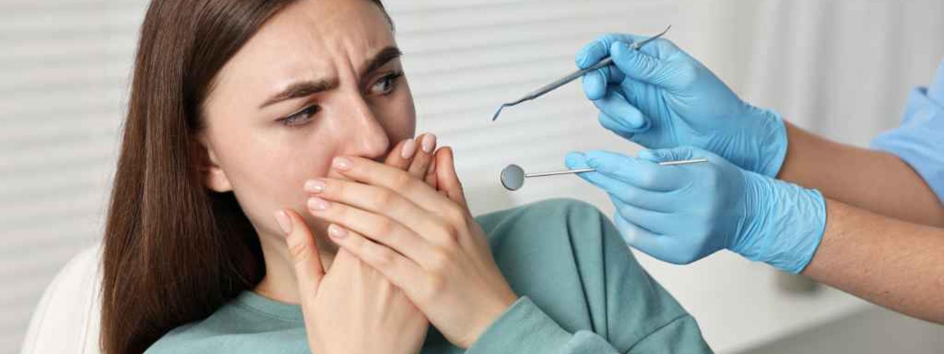 The Silent Epidemic: How Dental Anxiety Impacts Oral Health and What Science Says Helps Woman with dental anxiety shying away from dental tools at dentists office
